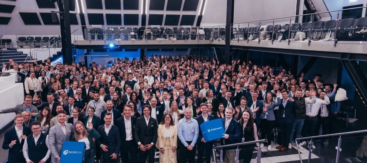 Gruppenfoto der Teilnehmenden der JCNetwork Days in einem Saal, viele winken in die Kamera